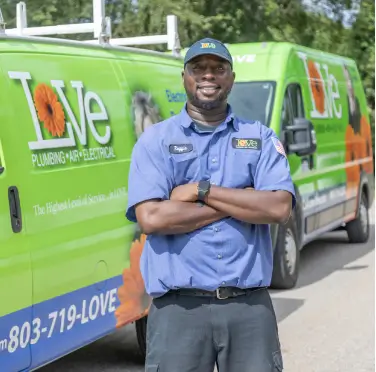 Love Plumbing Air & electrical technician smiling in front of service vans